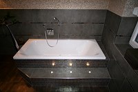 Das Bad nach der Neugestaltung in moderner Optik mit integrierten Strahlern im Sockel der Badewanne