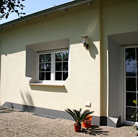 Fassade mit Wärmedämmung versehen, eingearbeitete Profile im Fenster- und Sockelbereich farblich abgesetzt