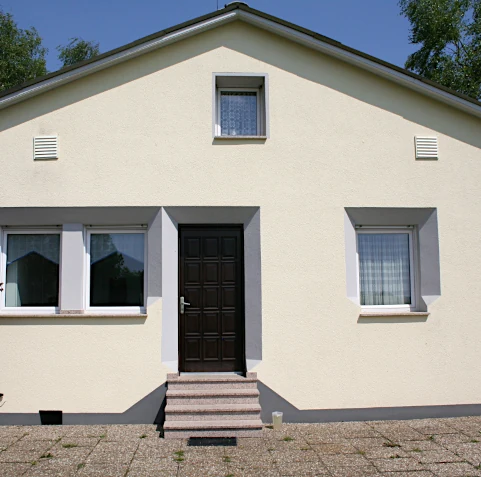 Hausfassade nach unserer Arbeit: Außendämmung, Neugestaltung mit eingelassenen Profilen, neuer Putz, ein frischer Anstrich, sowie eine neue Treppe