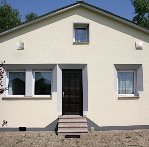 Hausfassade nach unserer Arbeit: Außendämmung, Neugestaltung mit eingelassenen Profilen, neuer Putz, ein frischer Anstrich, sowie eine neue Treppe